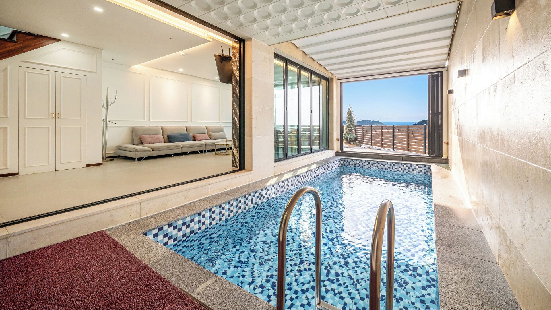 Piscina interior moderna con vistas claras al mar gracias a amplios ventanales.