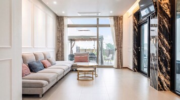 A modern living room with a sofa, a small round table, and a view through a glass door.