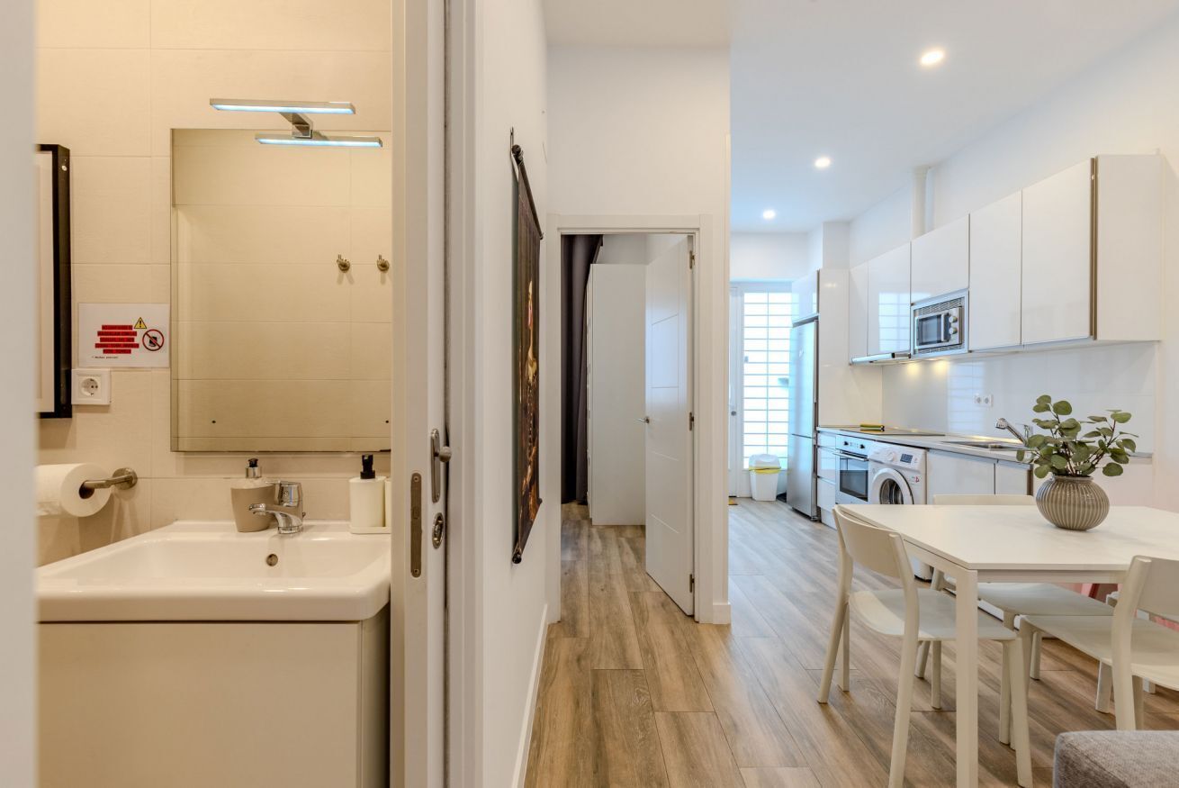 A modern kitchen with white cabinets, a microwave, and a sink.