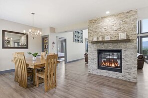 A modern living room with a fireplace, dining area with wooden chairs, and a large mirror. - Viewtopia - Luxury Smoky Mountain Cabin in Gatlinburg | Views, Hot Tub, Firepit & Game Loft (Gatlinburg)