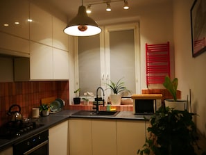 A modern kitchen with a central island, a microwave, and various plants. - Spacious, designer 3-room apartment in  center of warsaw (Warszawa)