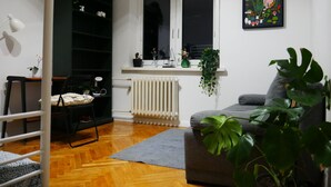 Een kamer met een stapelbed, een radiator, een grijze bank en een raam met uitzicht.