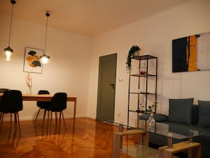 A modern living room with a glass coffee table, a sofa, a dining table with chairs, and a bookshelf. - Spacious, designer 3-room apartment in  center of warsaw (Warszawa)