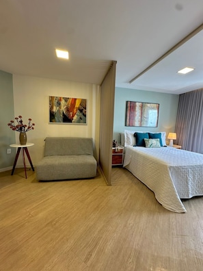 Ein Hotelzimmer mit einem Bett, einer Couch, einem kleinen Tisch mit einer Vase und zwei Bildern an der Wand.