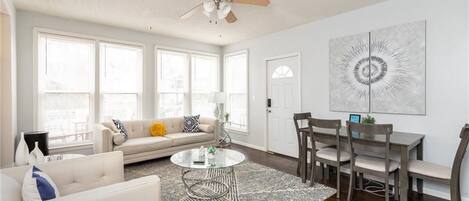 A spacious living room with a sofa, coffee table, and dining area with chairs.
