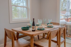A dining table set with glassware, bowls, and a bottle, surrounded by wooden chairs. - Oyster Haven/Waterfront Retreat on Lanes Creek/Mathews, VA (Hudgins)