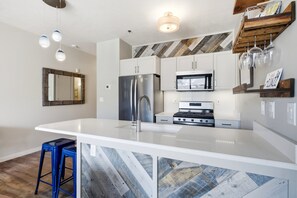 A modern kitchen with a large island, stainless steel appliances, and a herringbone-patterned backsplash. - Ski Escape at The Mason, AC , Hot Tubs, Near Deer Valley and Park City (Heber City)
