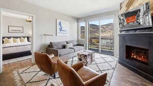Ein modernes Wohnzimmer mit einer Couch, Sesseln, einem Kamin und einem großen Fenster mit Blick.
