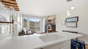 Eine moderne Küche mit einer großen Kochinsel, einem Kamin und Blick ins Freie.