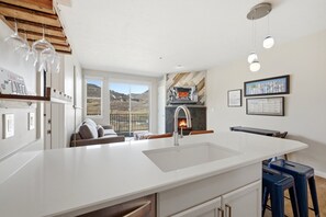 A modern kitchen with a large island, a fireplace, and a view of the outdoors. - Ski Escape at The Mason, AC , Hot Tubs, Near Deer Valley and Park City (Heber City)