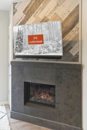 Ein Kamin mit darüber montiertem Fernseher, der eine Winterlandschaft zeigt.