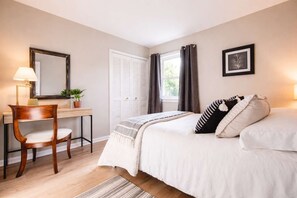 A bedroom with a bed, a desk, a chair, a window with curtains, and a framed picture on the wall. - Spacious Louisville home with backyard and parking (Louisville)