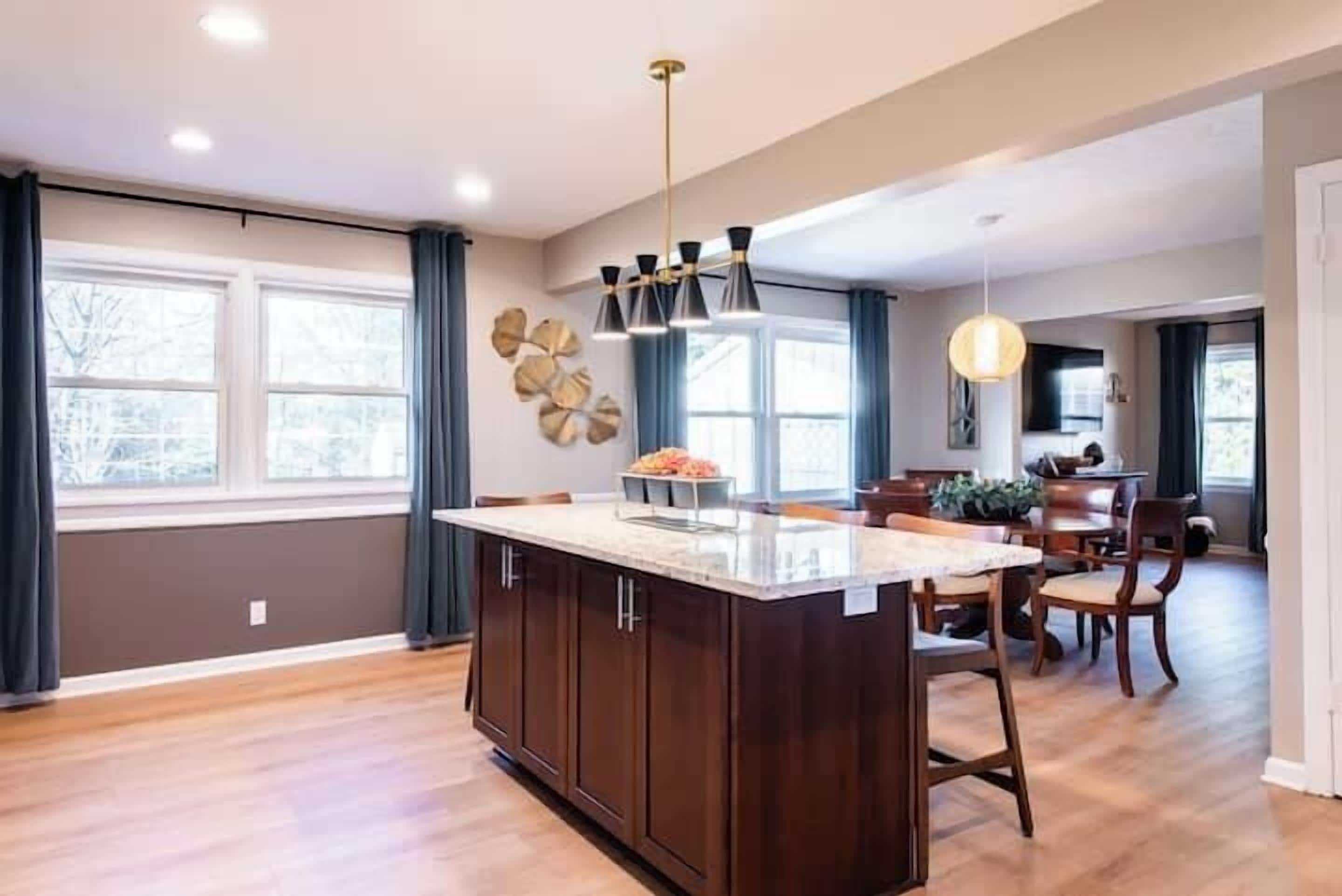 A modern kitchen with a central island, wooden cabinets, and a dining area with a table and chairs.