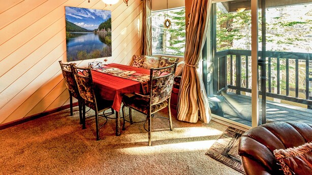 A dining area with a table, chairs, and a view of a lake through a glass door. - Peaceful 1 bedroom + Loft condo in Mammoth Lakes perfect for your getaway (Mammoth Lakes)