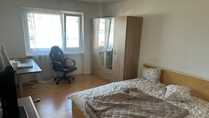 Ein Schlafzimmer mit Bett, Schreibtisch, Stuhl und Kleiderschrank.