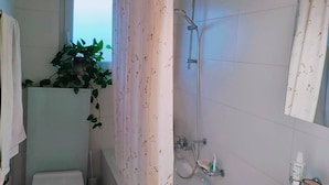 Ein Badezimmer mit Dusche, Toilette, Waschbecken und einem Blumentopf.