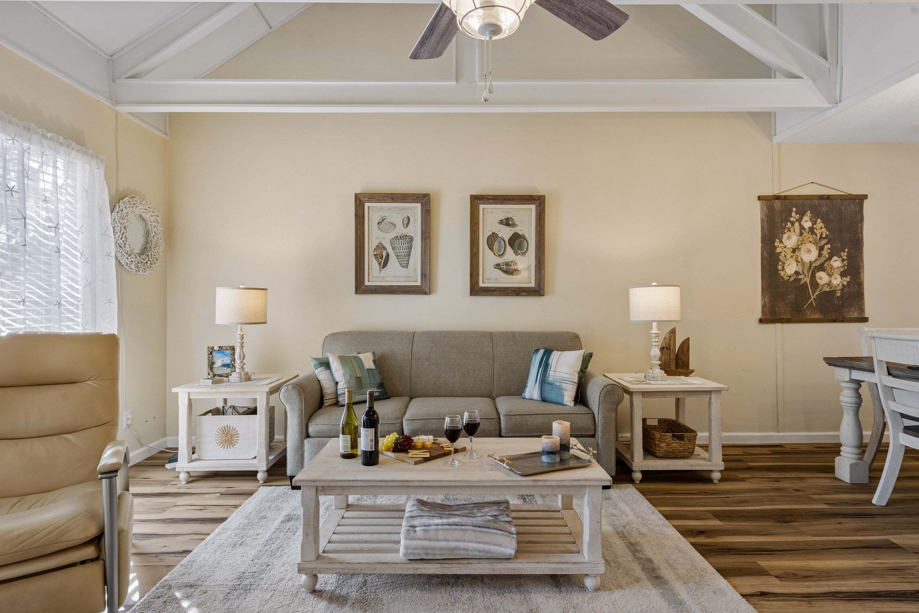 A living room with a sofa, two side tables with lamps, a coffee table with a tray of food and drinks, and framed artwork on the wall.