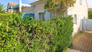 A two-story house with a tiled roof, a balcony, and a garden with various plants. - Residence Les Soleillades Et Scarlett (Palavas-les-Flots)