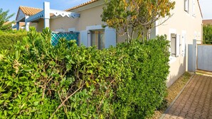 A two-story house with a tiled roof, a balcony, and a garden with various plants. - Residence Les Soleillades Et Scarlett (Palavas-les-Flots)