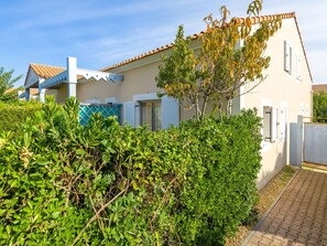 A two-story house with a tiled roof, a balcony, and a garden with various plants. - Residence Les Soleillades Et Scarlett (Palavas-les-Flots)