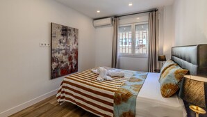 A hotel room with a bed, a window with curtains, an air conditioning unit, and a painting on the wall. - Bright and Fantastic 1H Apartment Arganzuela (Madrid)
