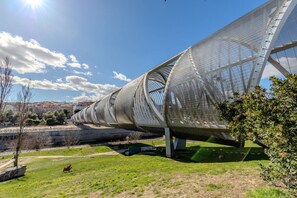A large, curved metal structure with a mesh-like surface, set in a grassy area with a clear sky and distant buildings. - Bright and Fantastic 1H Apartment Arganzuela (Madrid)