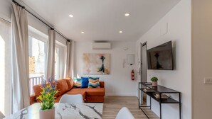 Un salon moderne avec un canapé, une table à manger agrémentée d’une plante en pot, un téléviseur et une cheminée.