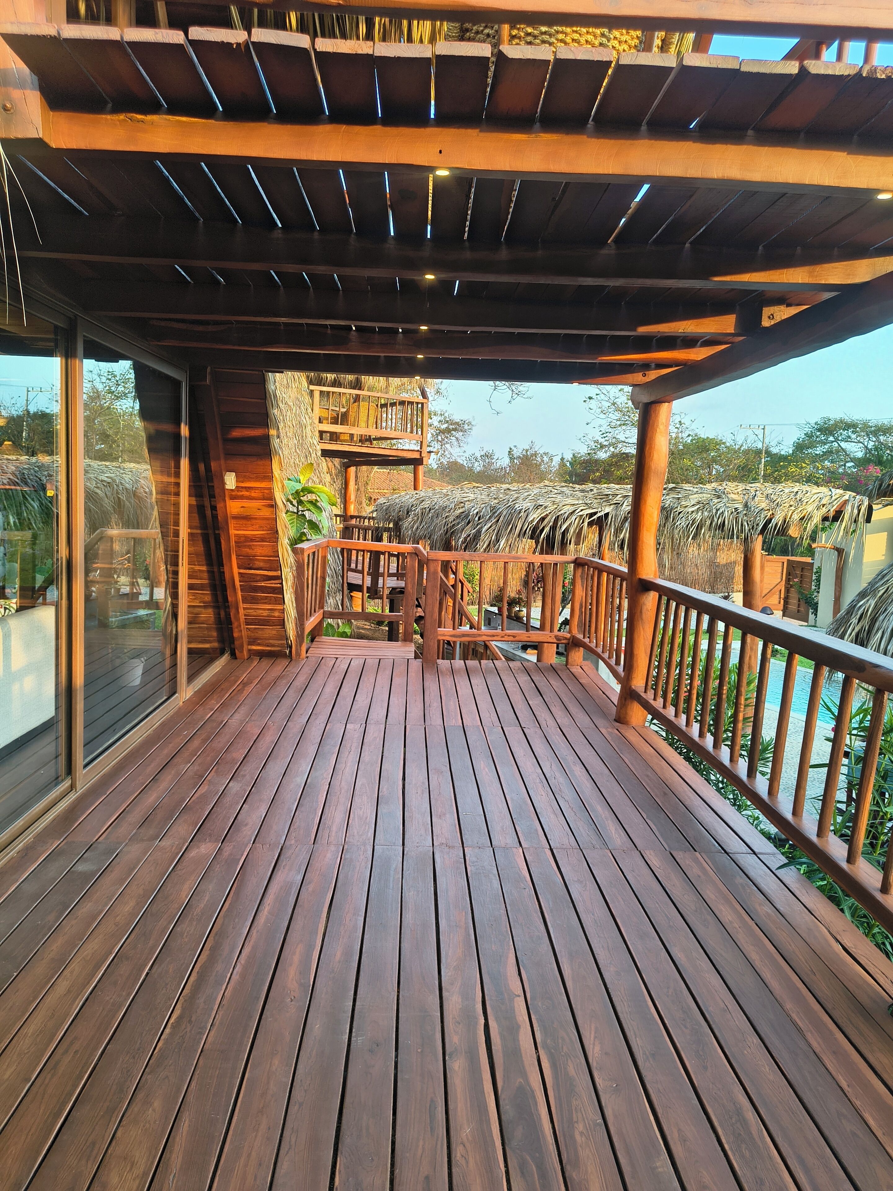 A wooden deck with a railing, a staircase, and a view of the surrounding landscape.