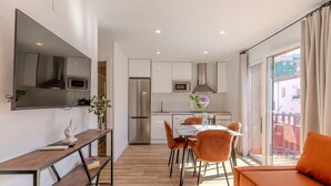 A modern kitchen with a refrigerator, microwave, and oven. There is a dining table with chairs and a sofa. - Bright and Fantastic 1H Apartment Madrid Rio (Madrid)