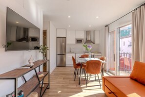 Cocina moderna con refrigerador, microondas y horno. Cuenta con una mesa de comedor con sillas y un sofá.