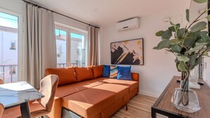 A modern living room with a sofa, a dining table, and a potted plant. - Bright and Fantastic 1H Apartment Madrid Rio (Madrid)