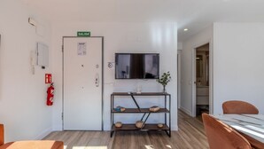 A hotel room with a bed, a TV, a shelf with decorative items, a fire extinguisher, and a door marked 'SALIDA'. - Bright and Fantastic 1H Apartment Madrid Rio (Madrid)