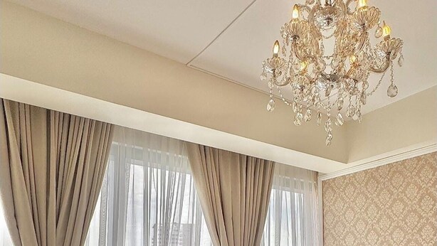 A bedroom with a large bed, a sofa, a chandelier, and a city view. - Room-modern Condo Room With City Views i (Davao)