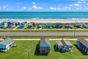A coastal residential area with houses, a road, and the ocean. - West End Galveston Beach House | Deck | Sleeps 9 (Galveston)