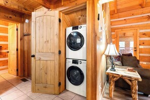 A wooden interior with a double washing machine, a small table with a lamp, and a couch. - Charming Retreat in Prime Location with Hot Tub and Large Deck (Gatlinburg)