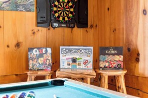 A pool table with three board games: Clue, Smokies Opoly, and 101 Games. - Charming Retreat in Prime Location with Hot Tub and Large Deck (Gatlinburg)