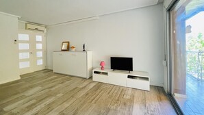 A modern living room with a flat-screen TV, a white cabinet, and a sliding glass door to a balcony. - 112-PALMAS COSTA: Refurbished flat with capacity for 7 people (SALOU)