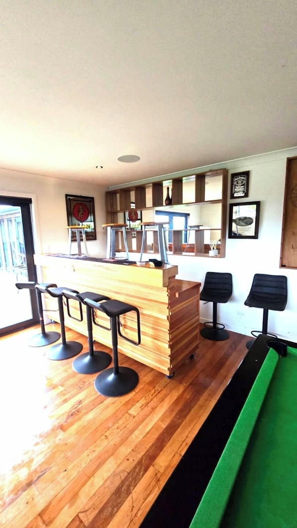 A bar area with stools, a counter, and a green cushioned bench.