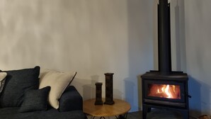 Un salon avec un canapé, une petite table ronde et un poêle à bois.