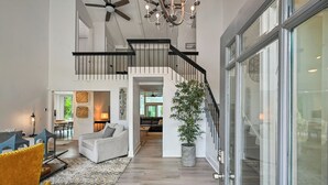 Uma sala de estar ampla com escada, área de refeições e uma janela grande.