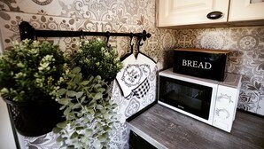 A kitchen with patterned wallpaper, a hanging plant, a white oven, and a 'BREAD' sign on the oven. - Riverside retreat with pool, summer kitchen, playground, and peaceful Drava views. (Pitomača)