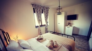 A hotel room with a bed, two bedside tables, a wardrobe, a television, and a window with curtains. - Riverside retreat with pool, summer kitchen, playground, and peaceful Drava views. (Pitomača)