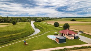 A house with a swimming pool, a fenced yard, and a river in the background. - Riverside retreat with pool, summer kitchen, playground, and peaceful Drava views. (Pitomača)