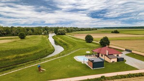 A house with a swimming pool, a fenced yard, and a river in the background.