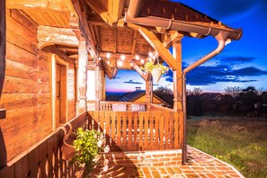Une maison en bois avec un porche, une jardinière suspendue et une vue sur le ciel.