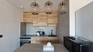 A modern kitchen with wooden cabinets, a built-in stove, a microwave, and three hanging pendant lights. - Spacious 3 Bedroom Apartment With Balcony and AC in Castellón (Castelló de la Plana)