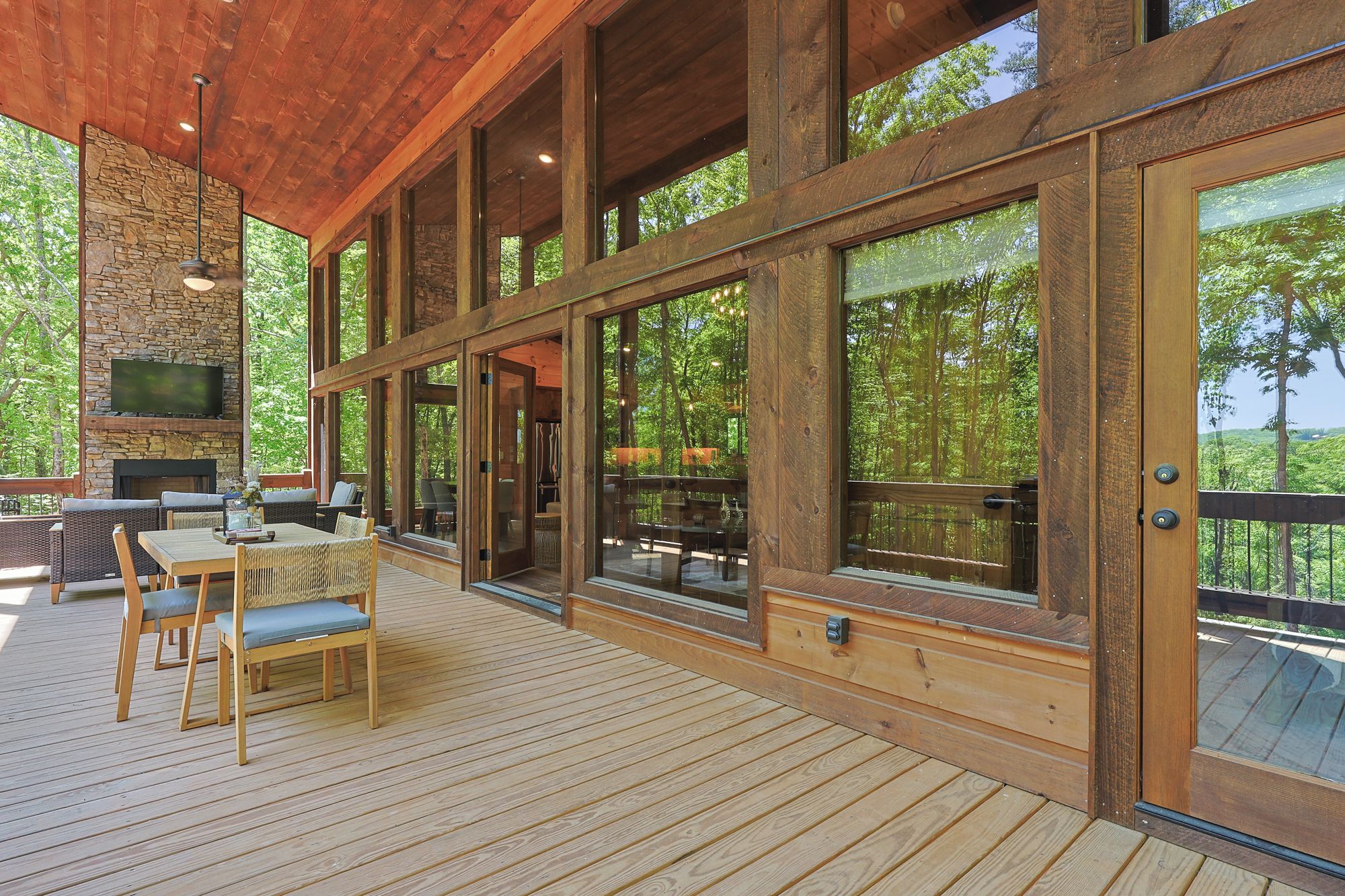 A wooden deck with outdoor seating and a stone fireplace.