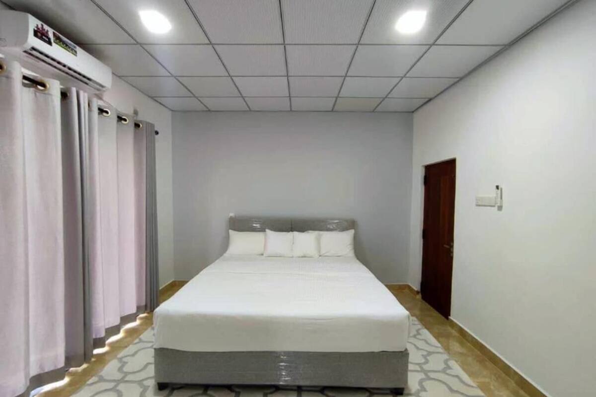 Een hotelkamer met een bed, gordijnen, een airconditioning en een deur.