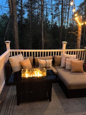 Eine Terrasse mit einer Couch und einem Tisch, umgeben von Bäumen und Lichterketten.