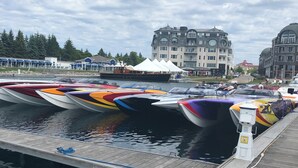 A marina with boats docked, a wooden dock, and buildings in the background. - Cheboygan Michigan Escape – River Views & Adventure Nearby.  (Cheboygan)
